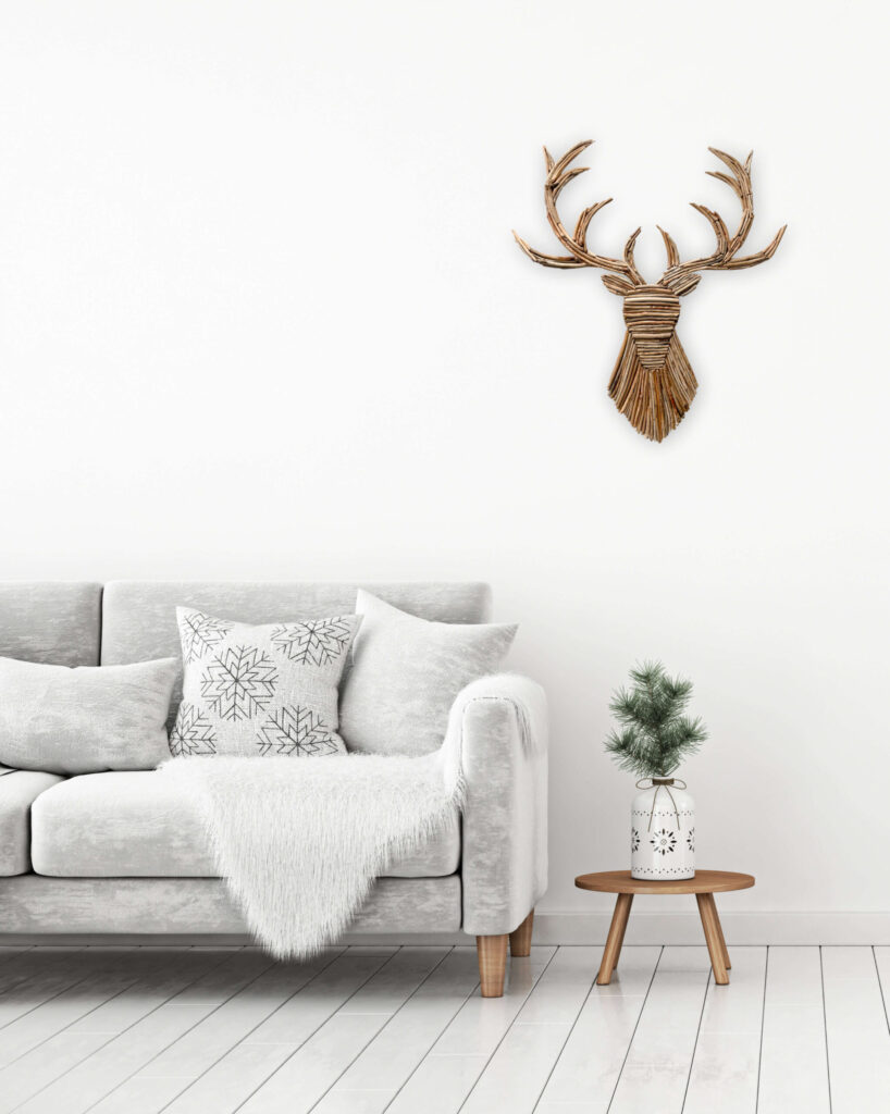 Silhouette de cerf en bois flotté accrochée au mur au dessus d'une table basse et d'un canapé cosy blanc