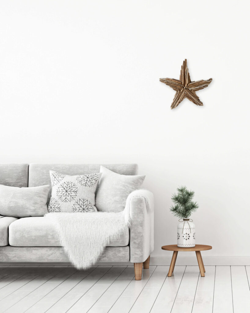 Silhouette d'étoile de mer en bois flotté accrochée au mur au dessus d'une table basse et d'un canapé cosy blanc