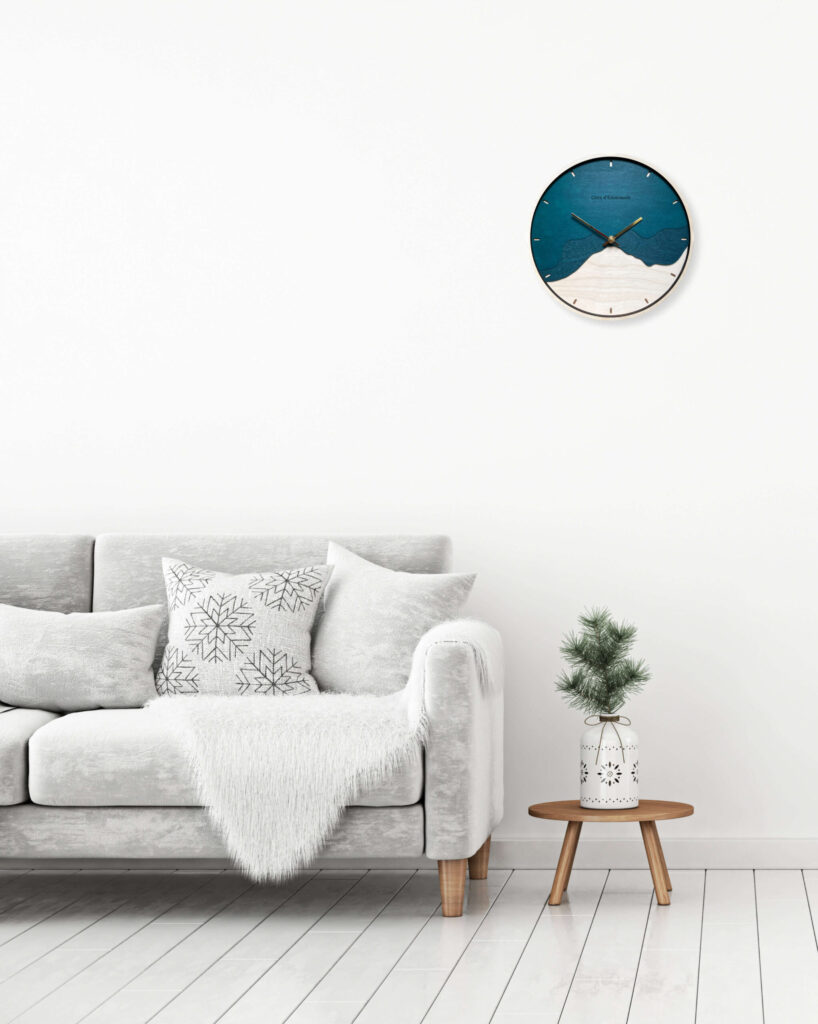 Horloge couleur émeraude accrochée au mur au dessus d'une table basse et d'un canapé cosy blanc