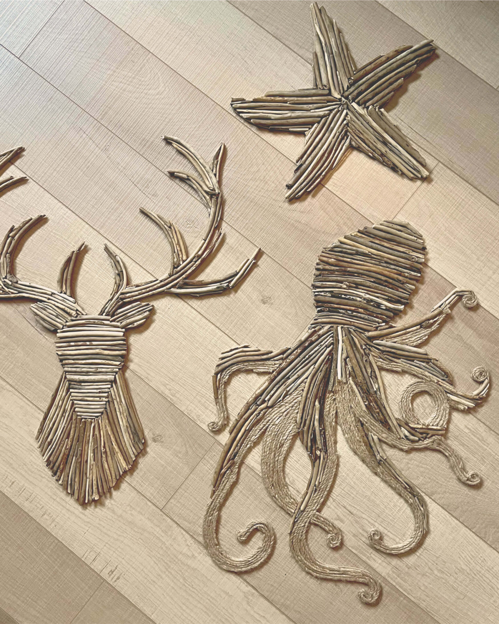 Photo de 3 décorations en bois flotté sur du parquet : une étoile de mer, un cerf et un octopus